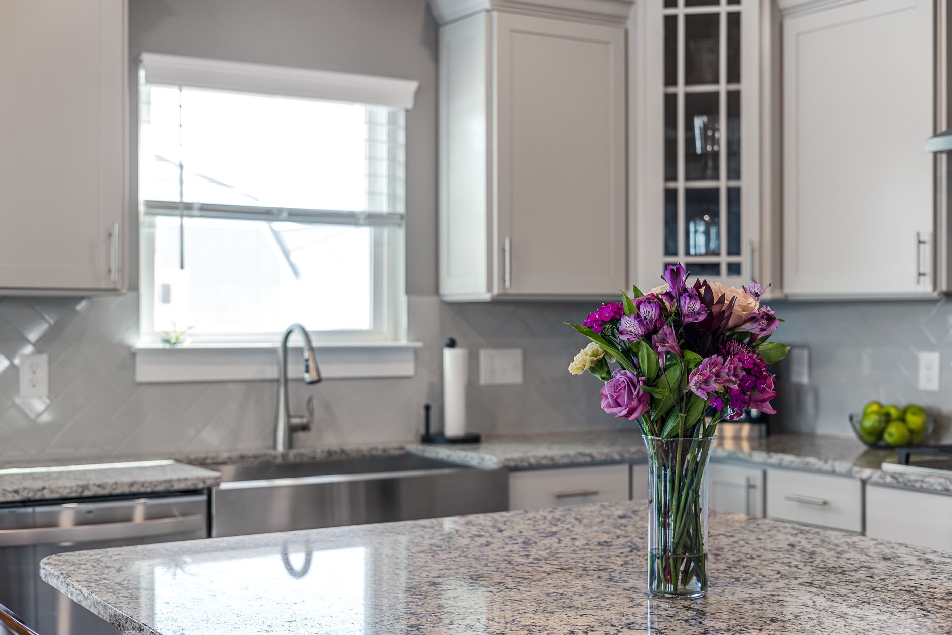 A vase of purple and pink alstroemeria on a granite kitchen counter in a bright kitchen