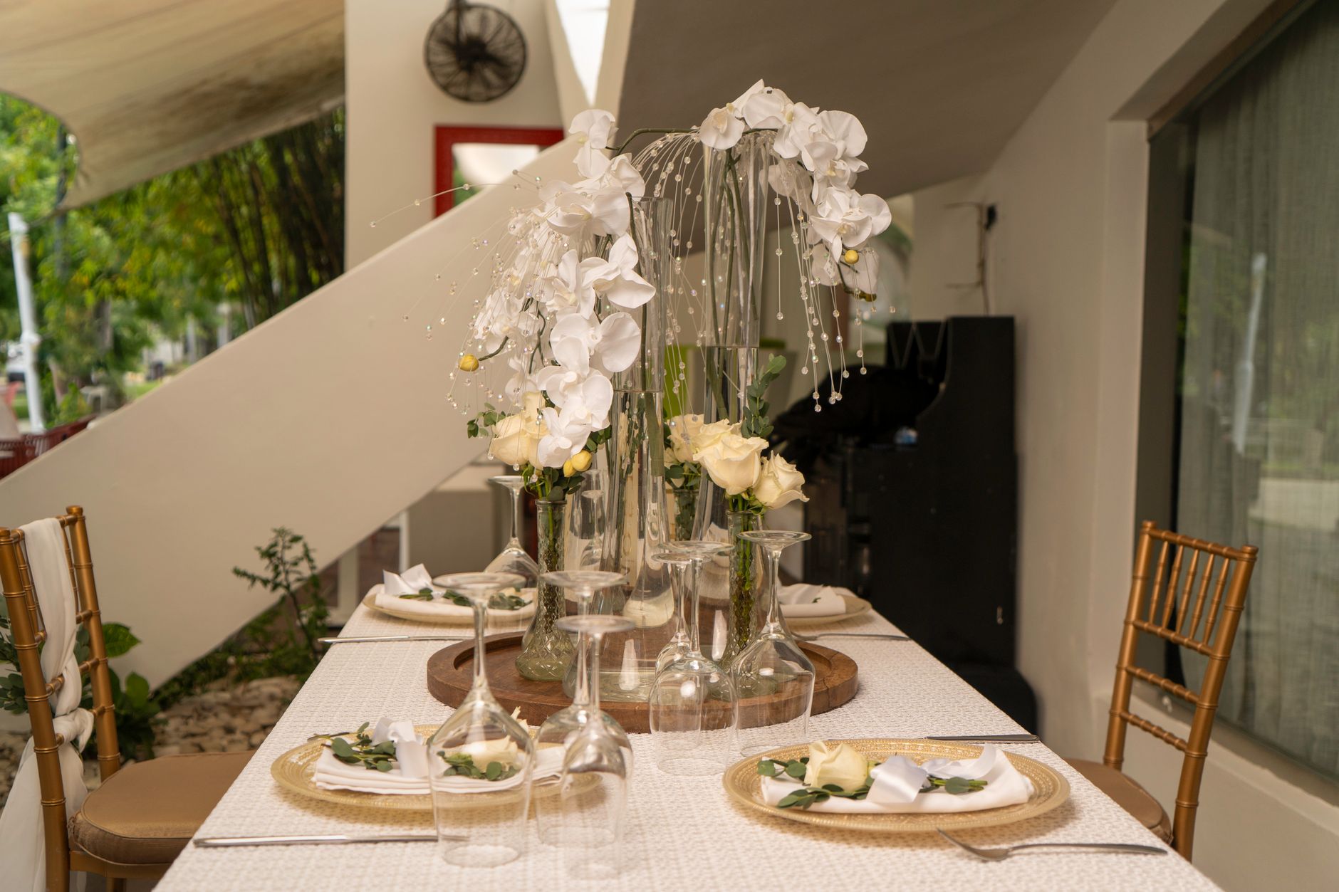 A long table set with tall glass vases of white orchids and cream roses and glassware