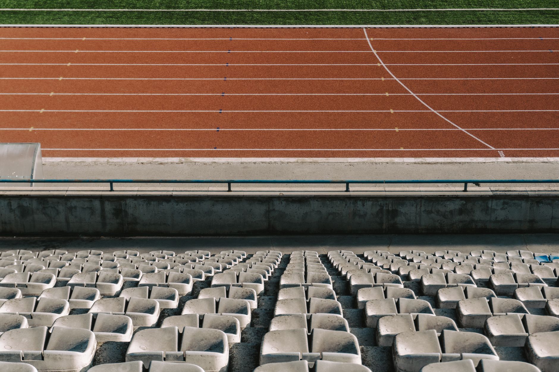 Rows of empty stadium seats facing a red running track and green field