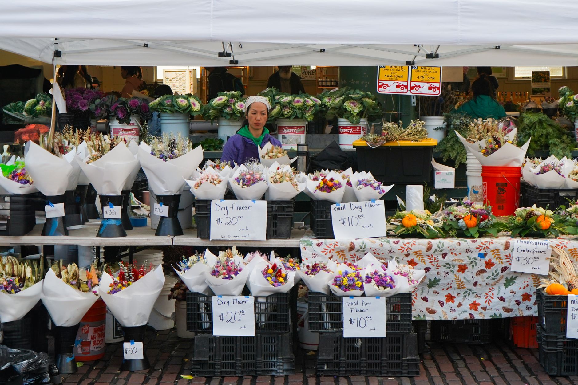 A market flower stall with wrapped bouquets in buckets and handwritten price signs