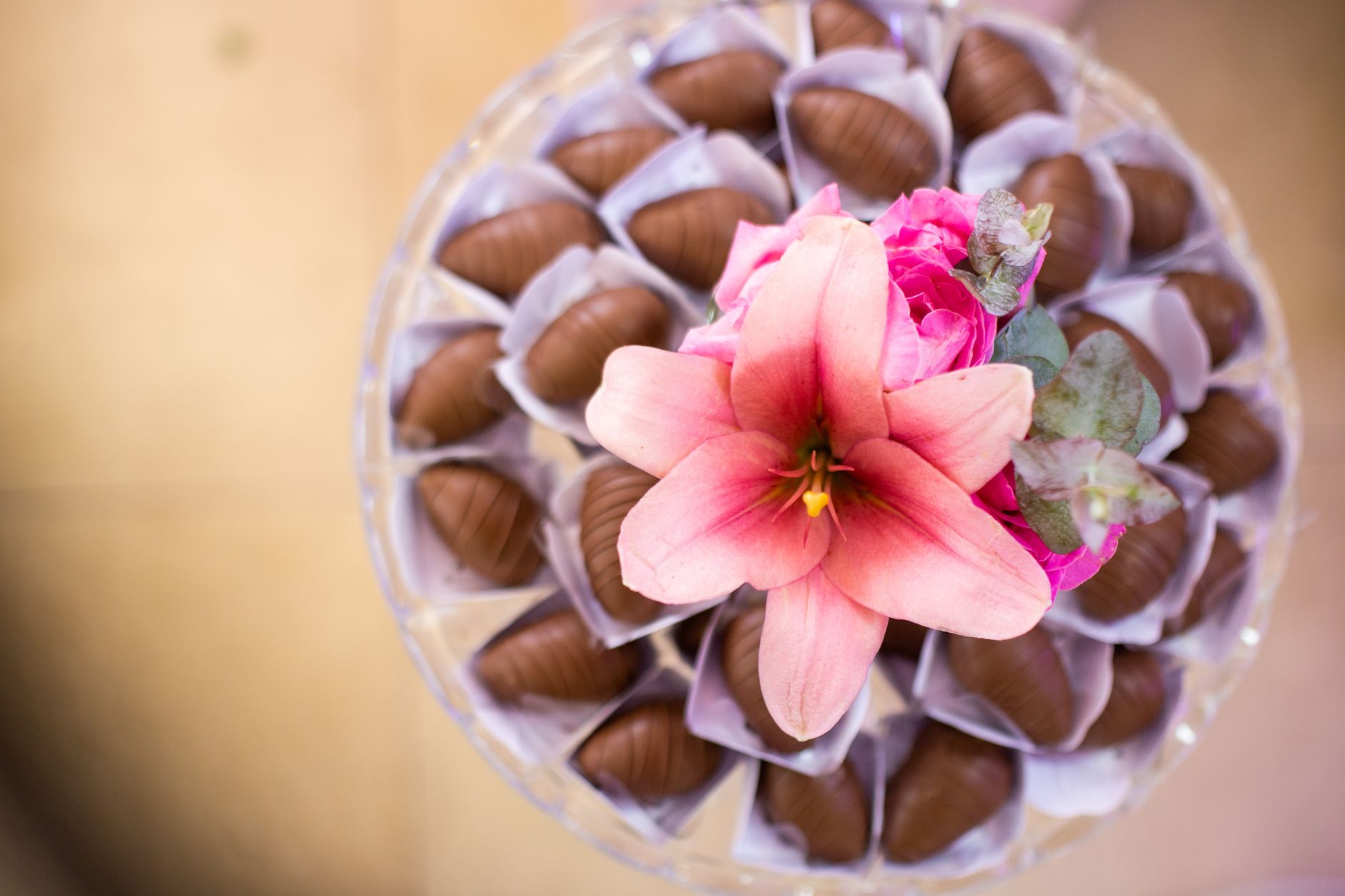 An overhead view of a pink lily on a platter of chocolates in paper cups