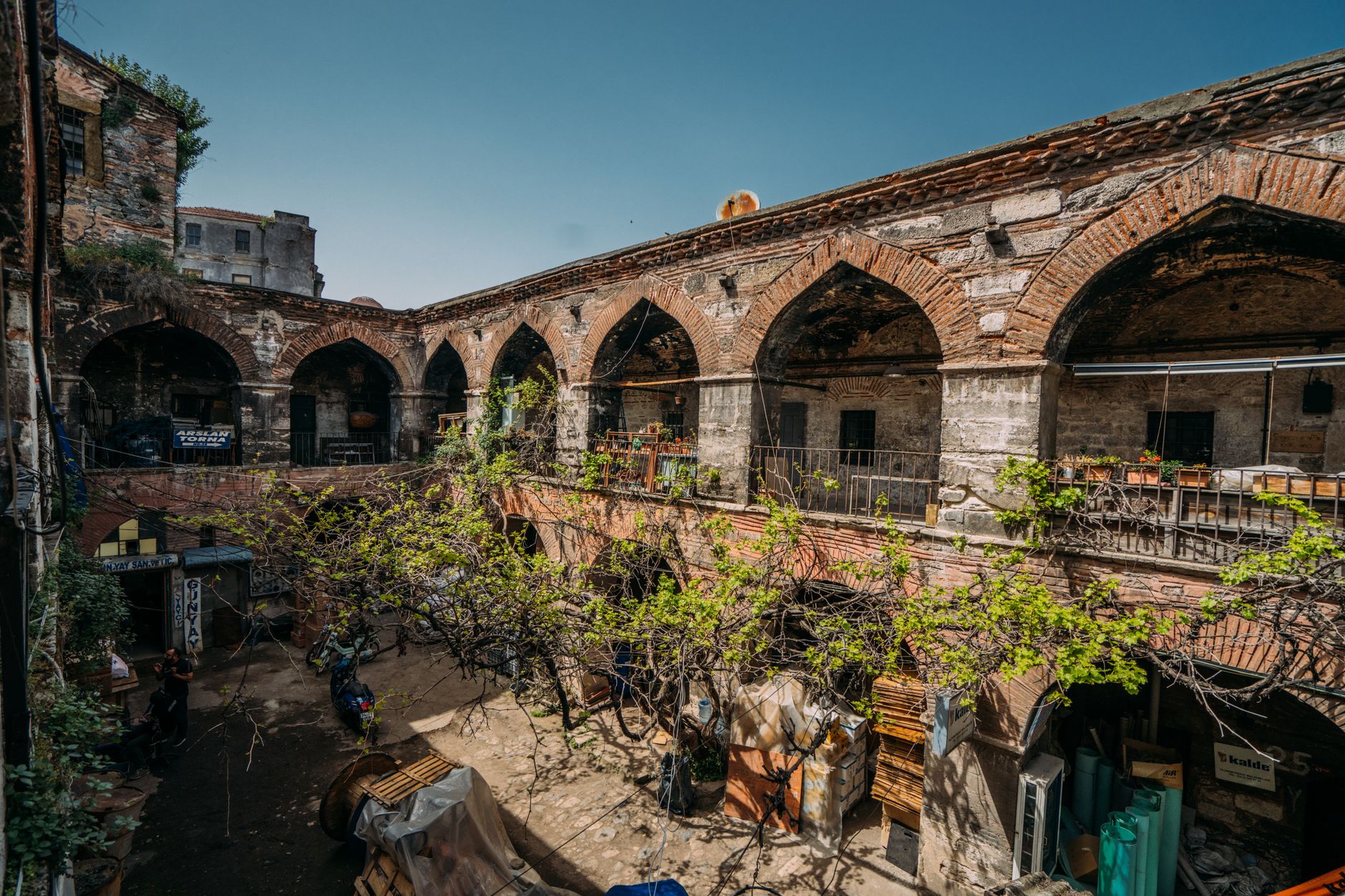 An old brick courtyard with stone arches and green vines under a blue sky