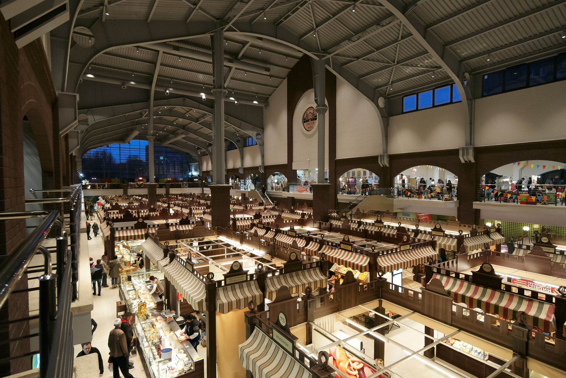 The inside of a large indoor market hall with striped awnings over stalls